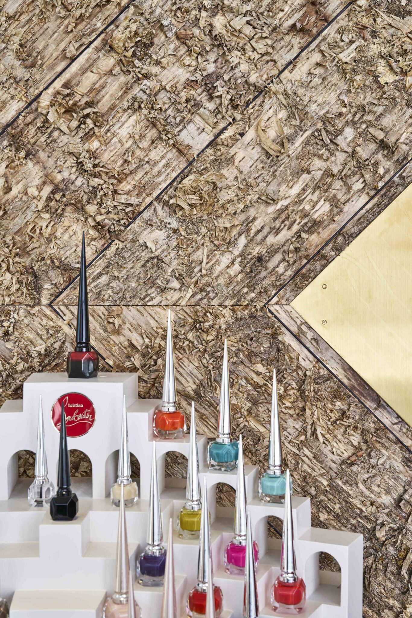 Bark House gold birch wall covering panels at an angle behind Louboutin nail polishes